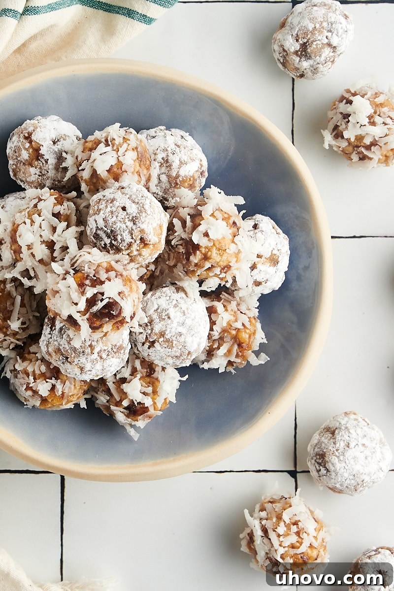 Overhead view of a bowl full of date balls alongside more on a countertop, ready for enjoyment