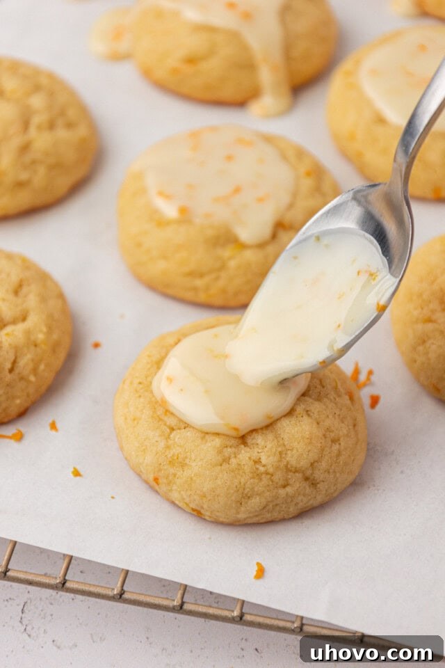 orange icing being spooned onto an orange cookie