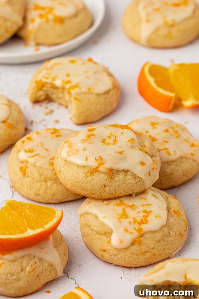 glazed orange cookies and orange slices scattered on a white surface