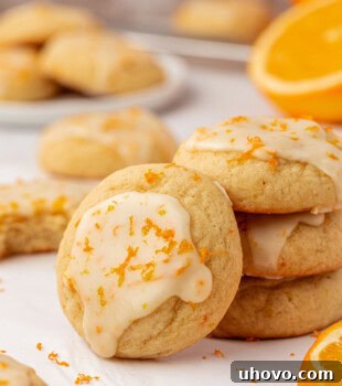 a glazed orange cookie leaned against a stack of three cookies