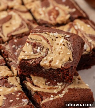 A tahini brownie resting on top of more brownies on parchment paper, highlighting the swirl