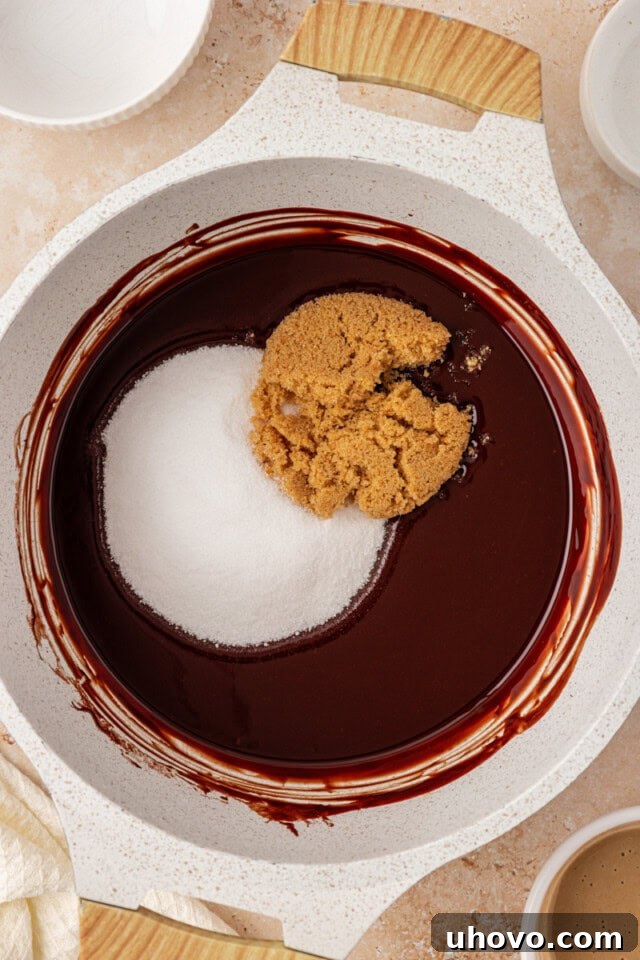 overhead view of sugar and brown sugar added to melted butter and chocolate