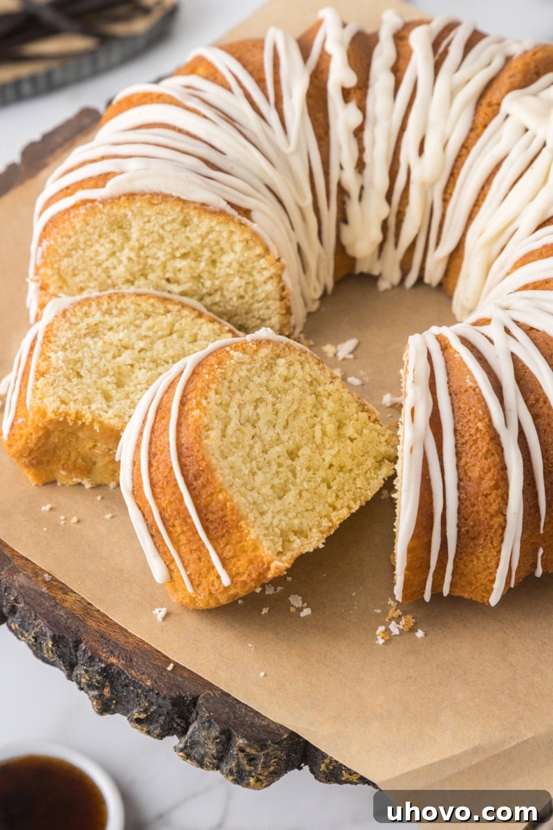 Vanilla Bundt cake with vanilla bean glaze on a parchment-lined wooden cake stand