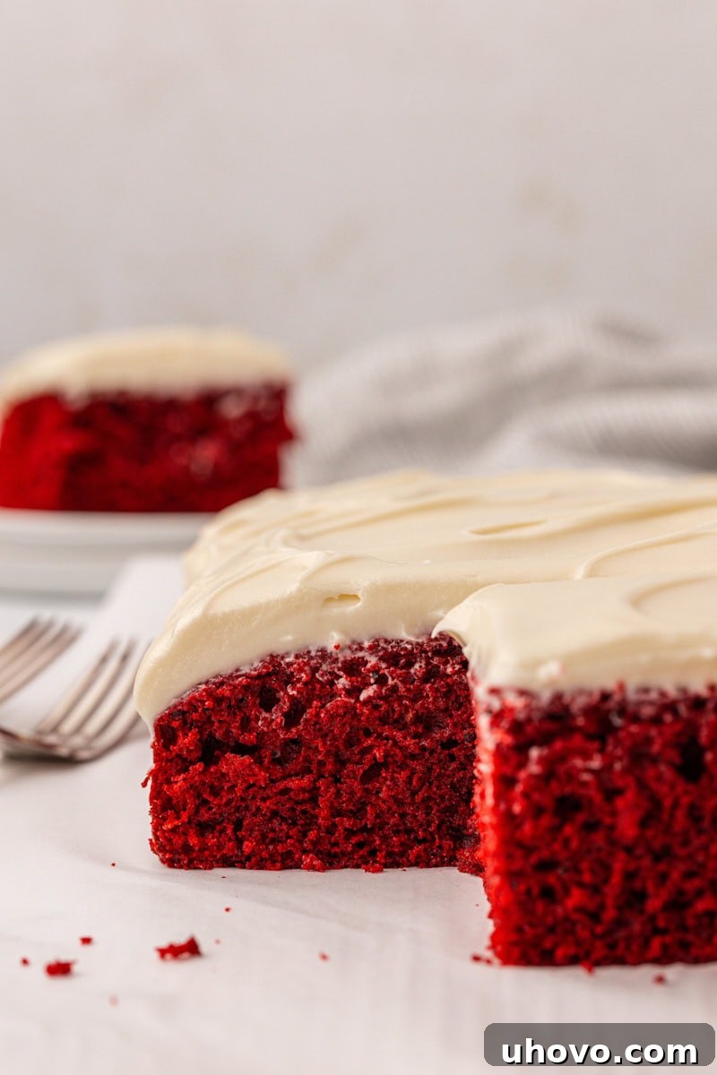 partially sliced red velvet sheet cake with cream cheese frosting 