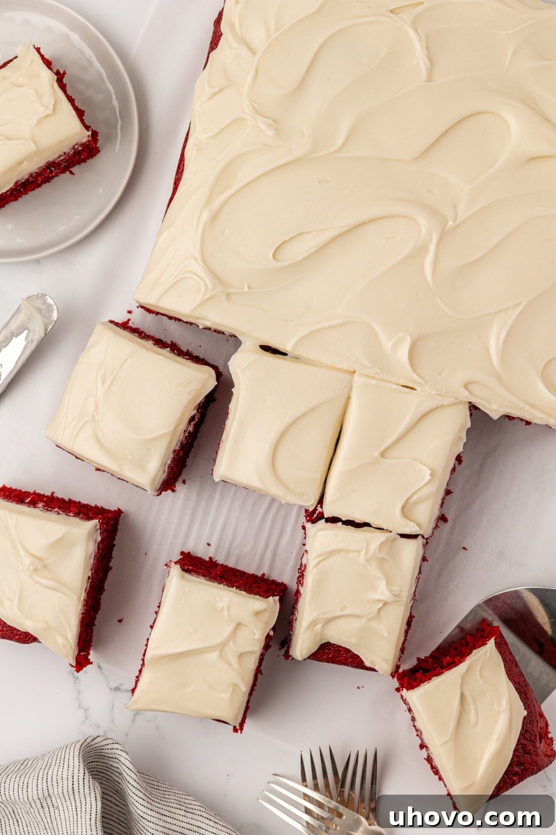 red velvet sheet cake with cream cheese frosting partially sliced into squares