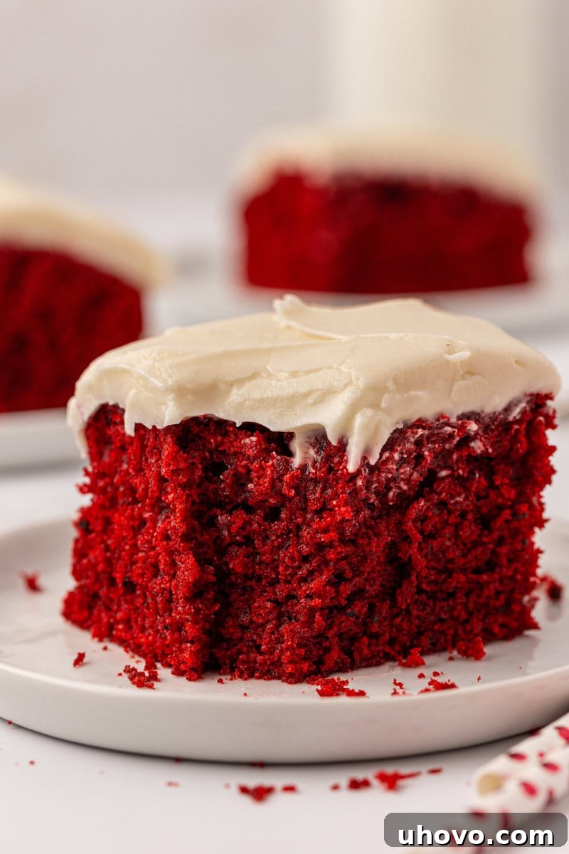 a slice of red velvet sheet cake with cream cheese frosting with a bite missing from the front corner