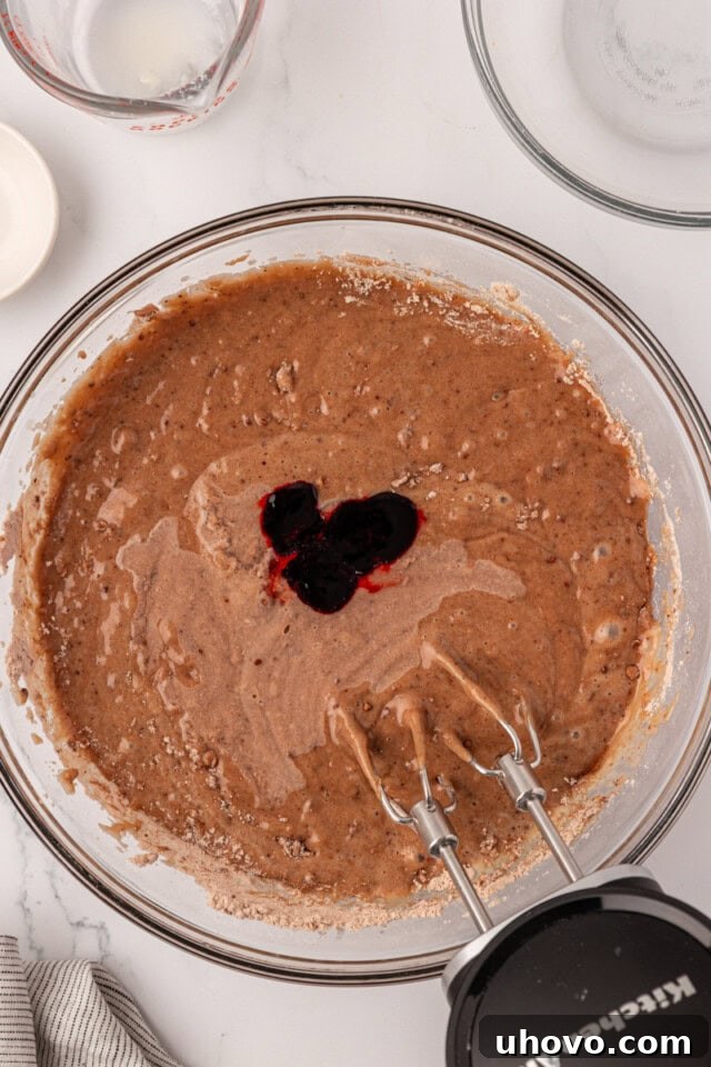 overhead view of red food coloring added to cake batter