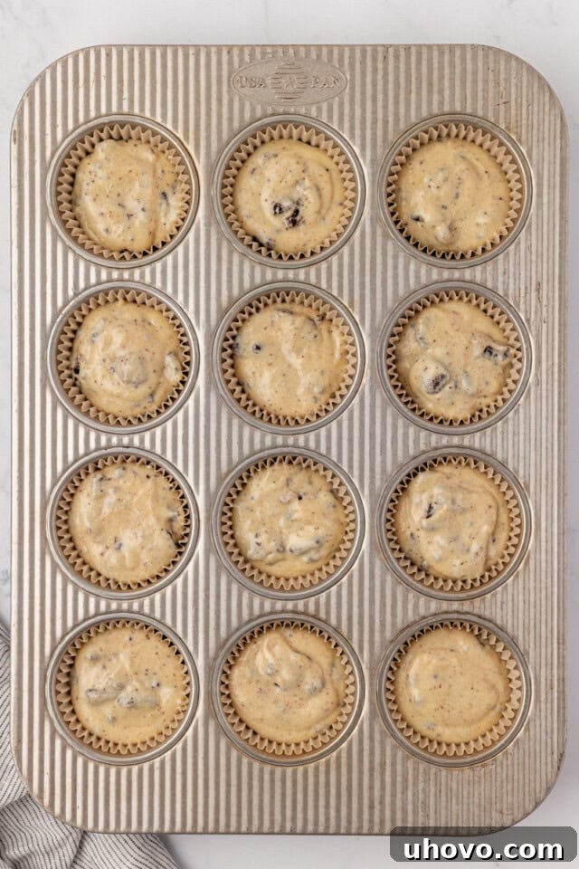 overhead view of cookies and cream cupcake batter divided into a 12-cup muffin pan ready to go into the oven