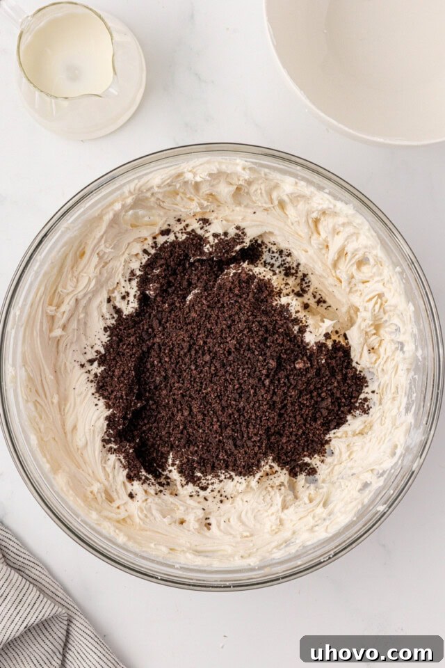 overhead view of chocolate sandwich cookie crumbs added to vanilla buttercream