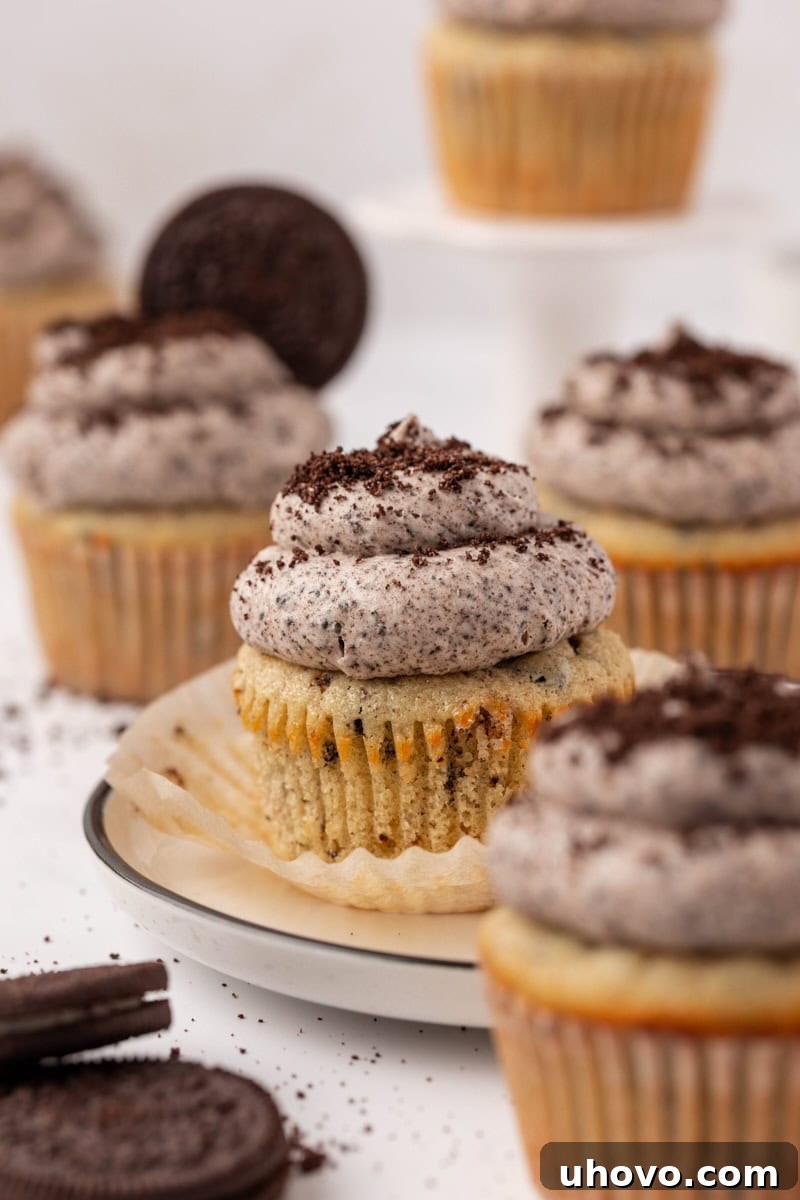 a cookies and cream cupcake on a white plate surrounded by more cupcakes
