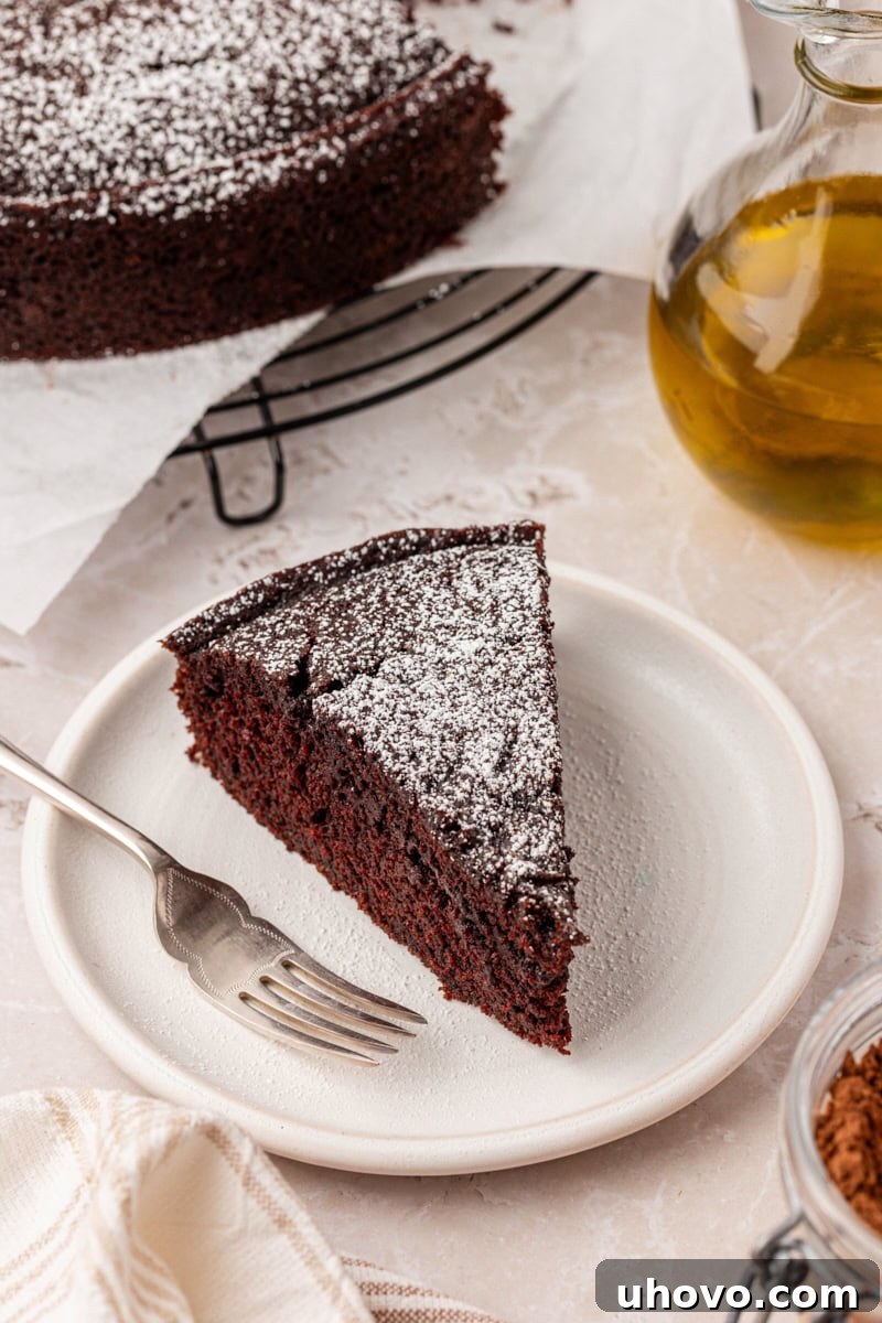 A perfect slice of chocolate olive oil cake presented on a white plate, showcasing its beautiful crumb and simple elegance.