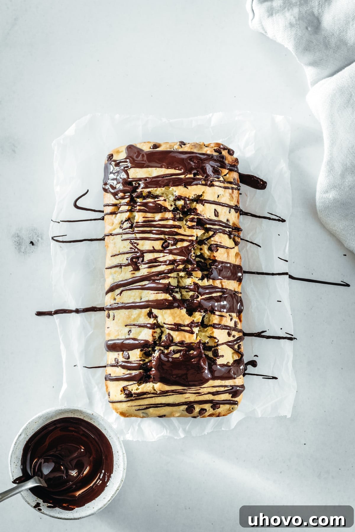 An overhead view of the Chocolate Chip Cashew Bread loaf after it has been elegantly drizzled with melted dark chocolate, showcasing the appealing finish.