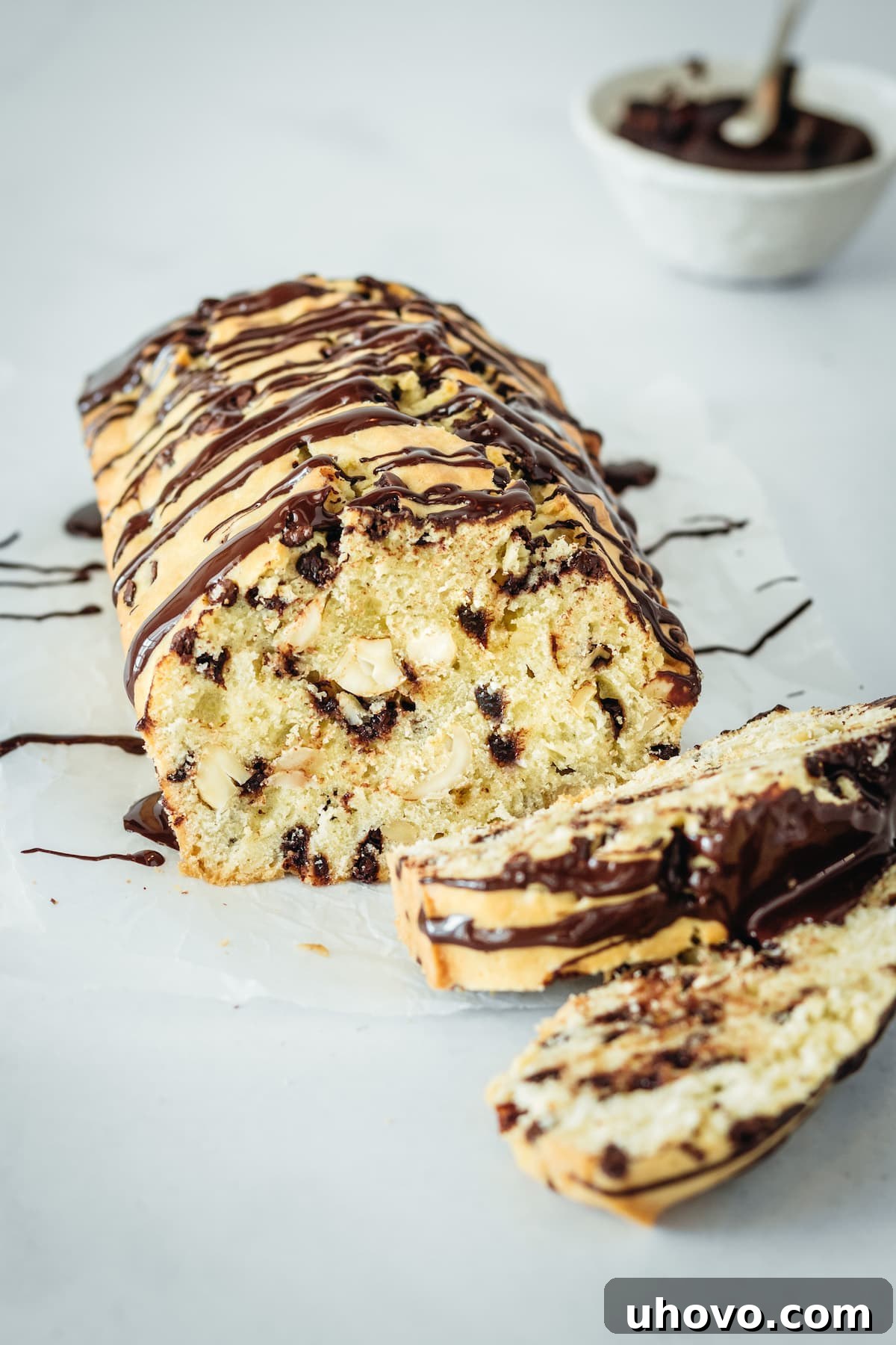 A beautiful Chocolate Chip Cashew Bread loaf with two slices cut and placed alongside, showcasing its rich texture and elegant chocolate drizzle.