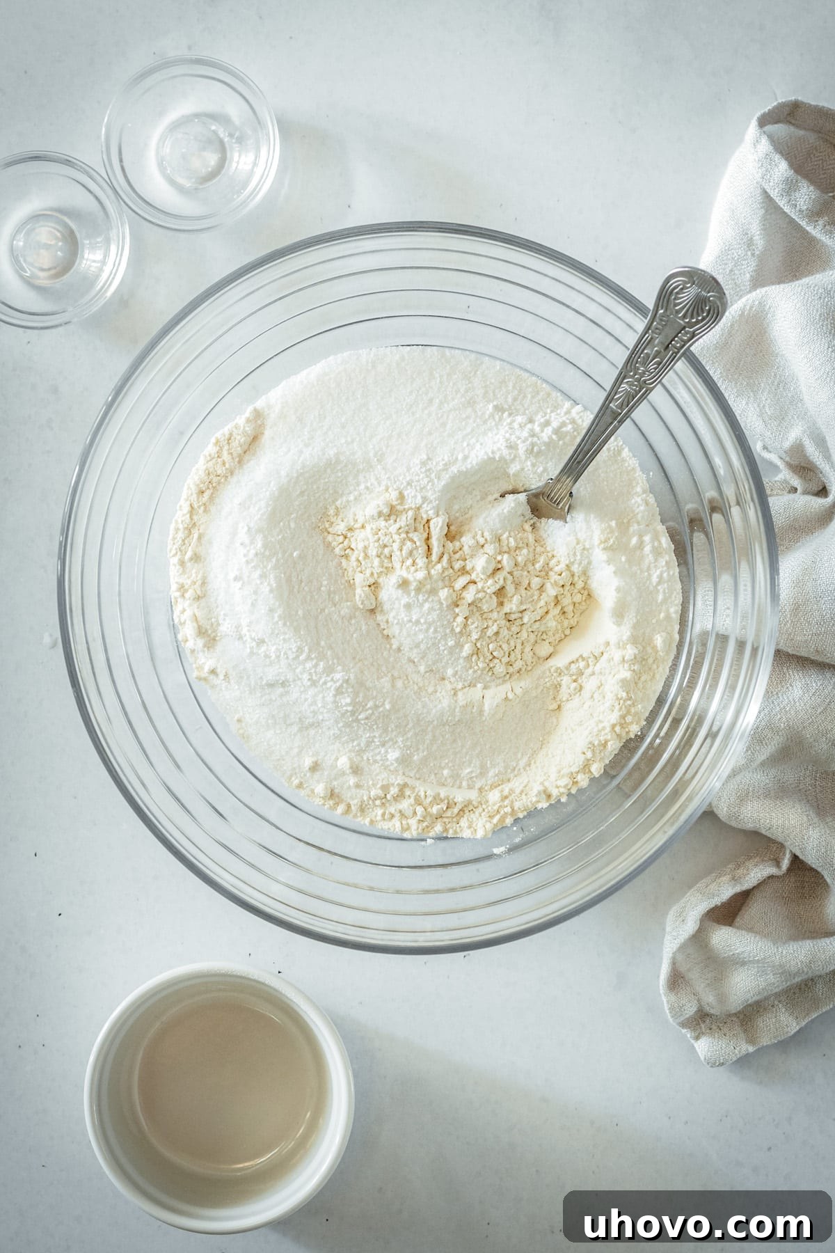 An overhead view of a large glass mixing bowl containing the perfectly whisked dry ingredients: all-purpose flour, granulated sugar, baking powder, and salt, ready for the wet ingredients.