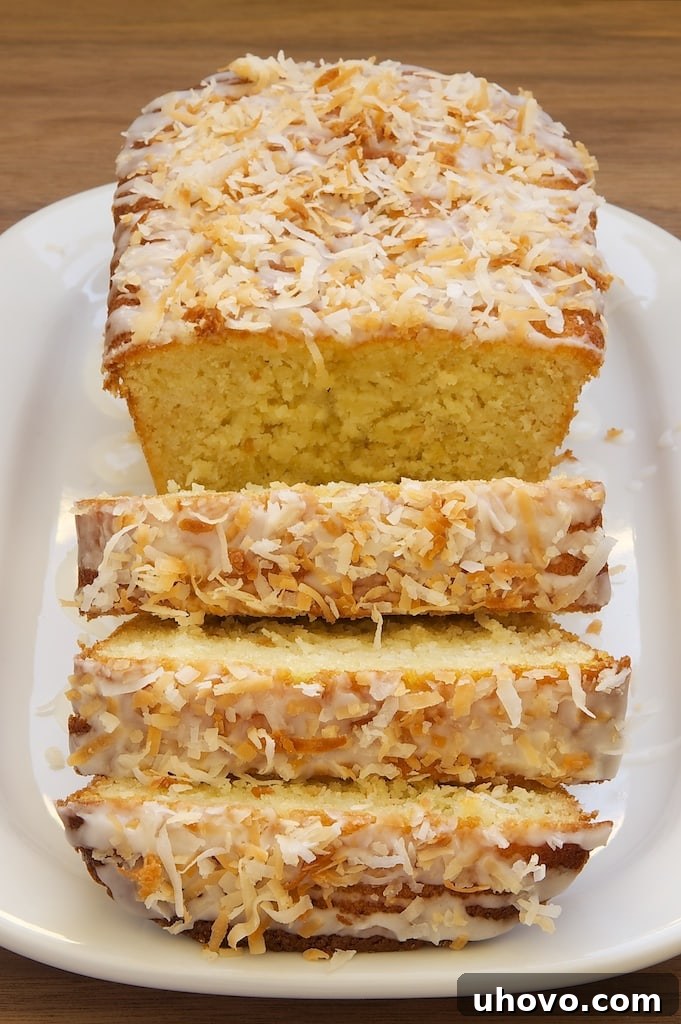 A perfectly sliced Coconut Buttermilk Pound Cake, showcasing its moist texture and golden-brown crust, served on a pristine white plate.
