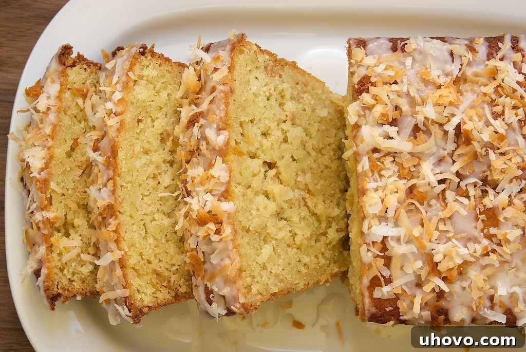 Overhead view of a beautiful Coconut Buttermilk Pound Cake with three slices neatly cut, garnished with toasted coconut.