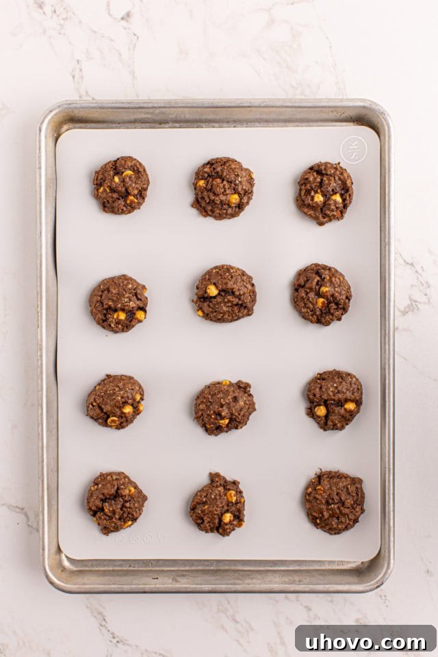 Overhead view of freshly baked chocolate butterscotch cookies on a baking sheet, golden and slightly puffed.