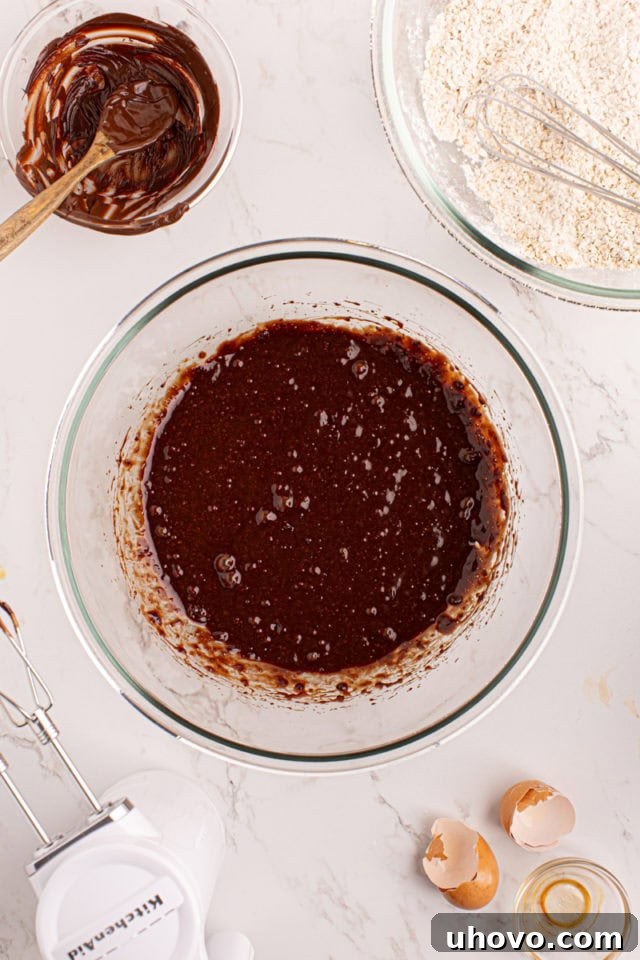 Overhead view of the combined wet ingredients for chocolate butterscotch cookies, including melted chocolate, in a bowl after mixing.