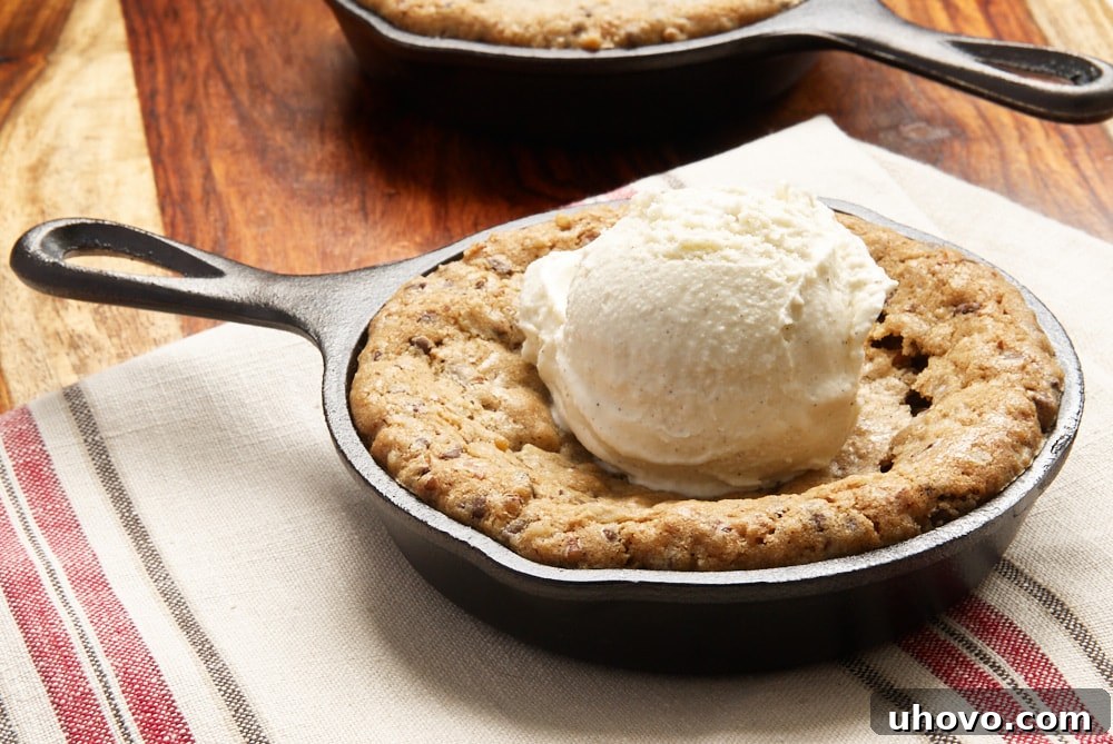 A mini skillet chocolate chip cookie topped with a generous scoop of vanilla bean ice cream, creating a perfect dessert sundae.