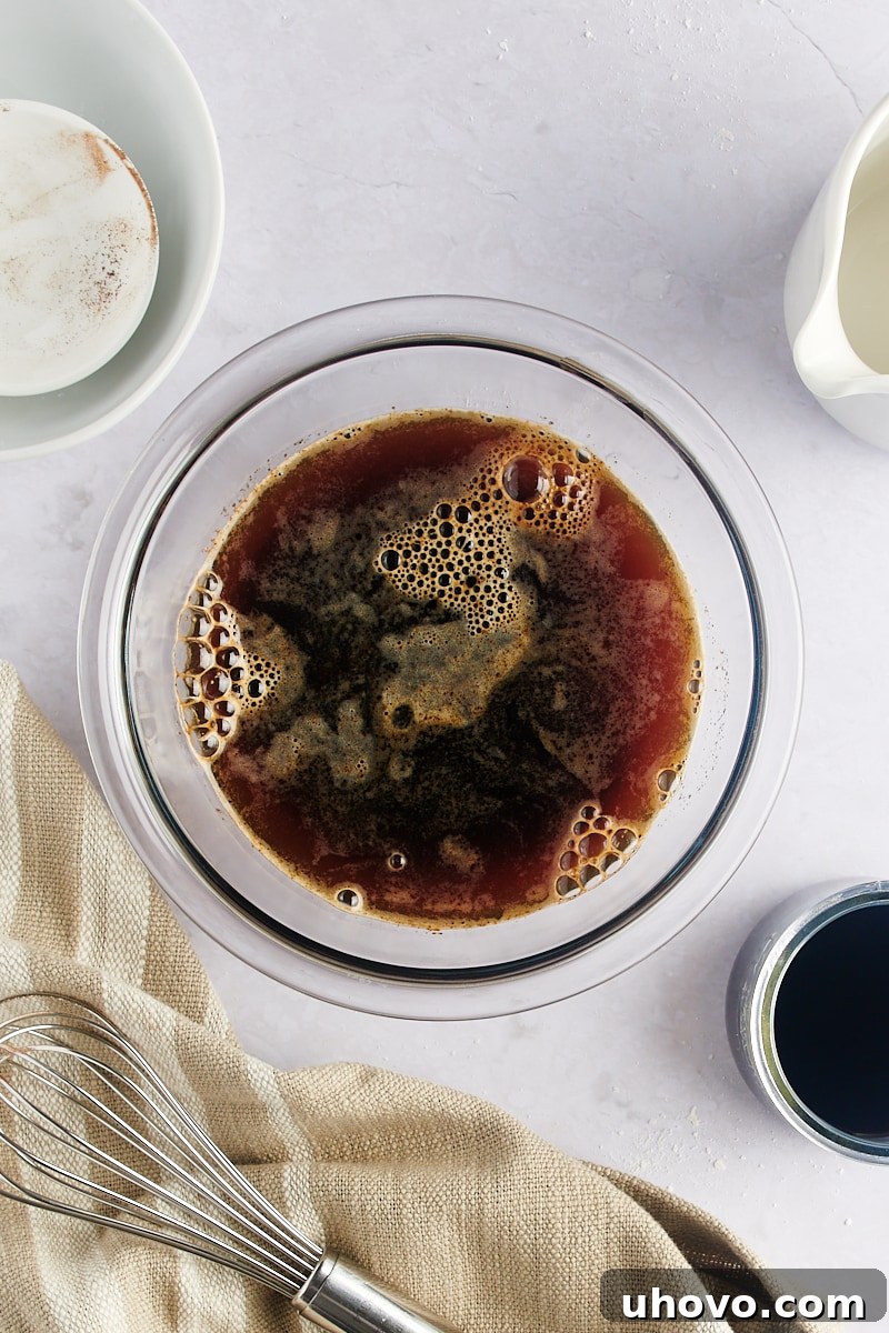 Overhead view of the liquid coffee mixture in a mixing bowl, with no visible sugar grains.