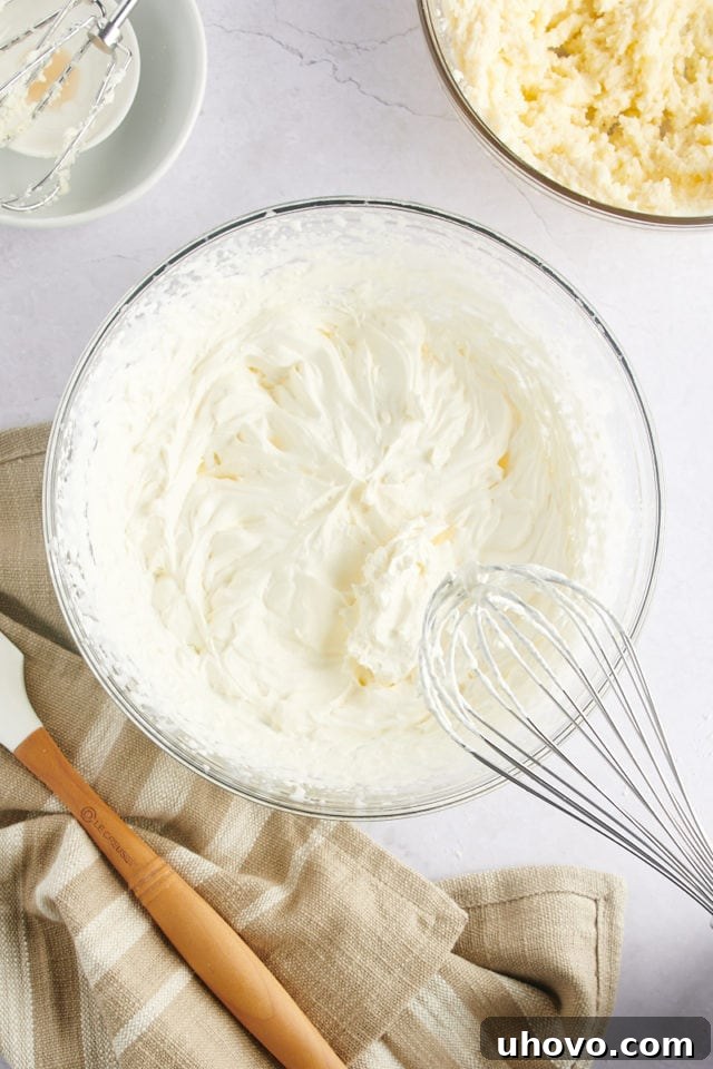 Whipped heavy cream in a mixing bowl with a whisk, showing stiff peaks.
