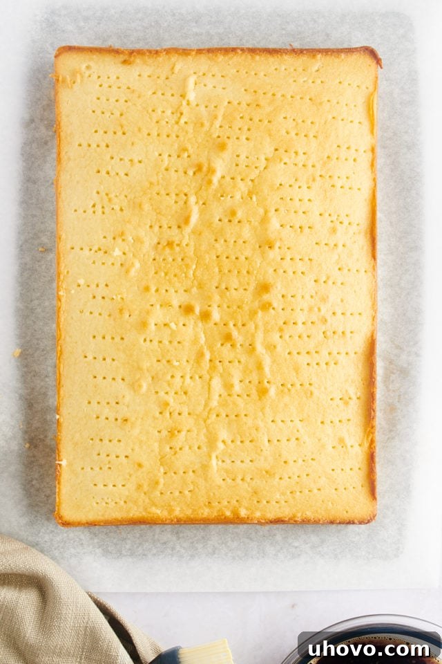 Baked vanilla cake with numerous fork holes poked into its surface.