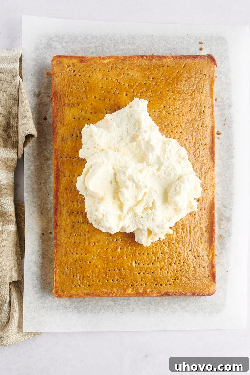 Mascarpone frosting dolloped on top of a coffee-soaked cake, ready to be spread.