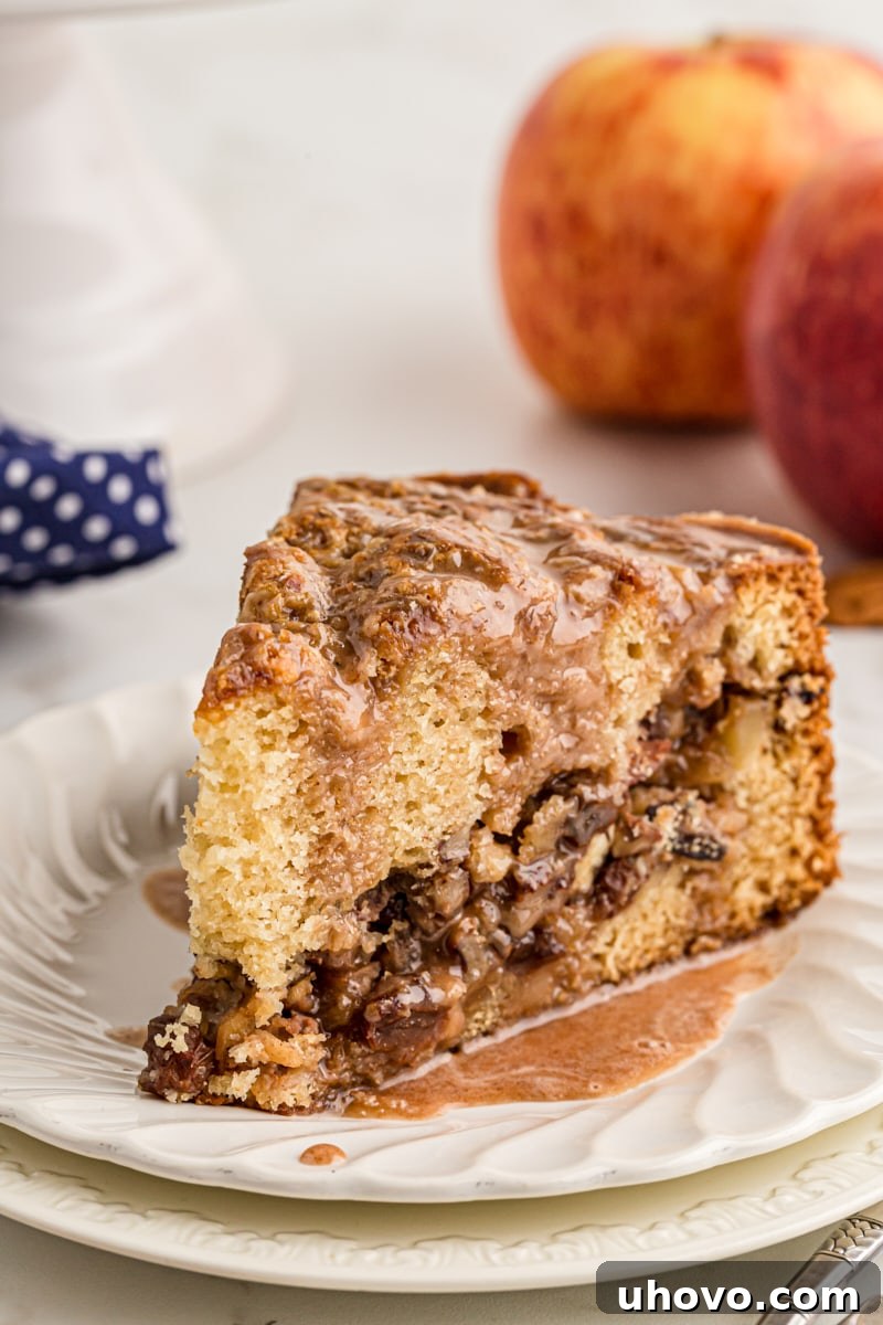 A delectable slice of apple streusel coffee cake on a white plate, ready to be enjoyed with a hot beverage
