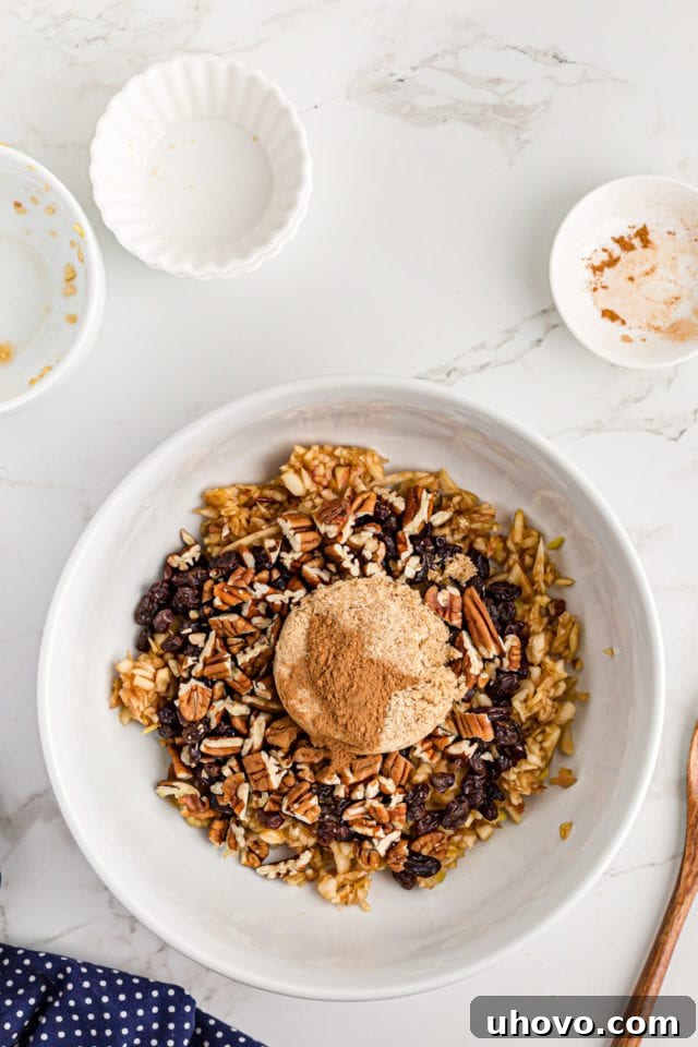 Overhead view of streusel ingredients (chopped apples, currants, pecans, brown sugar, cinnamon) being combined in a mixing bowl