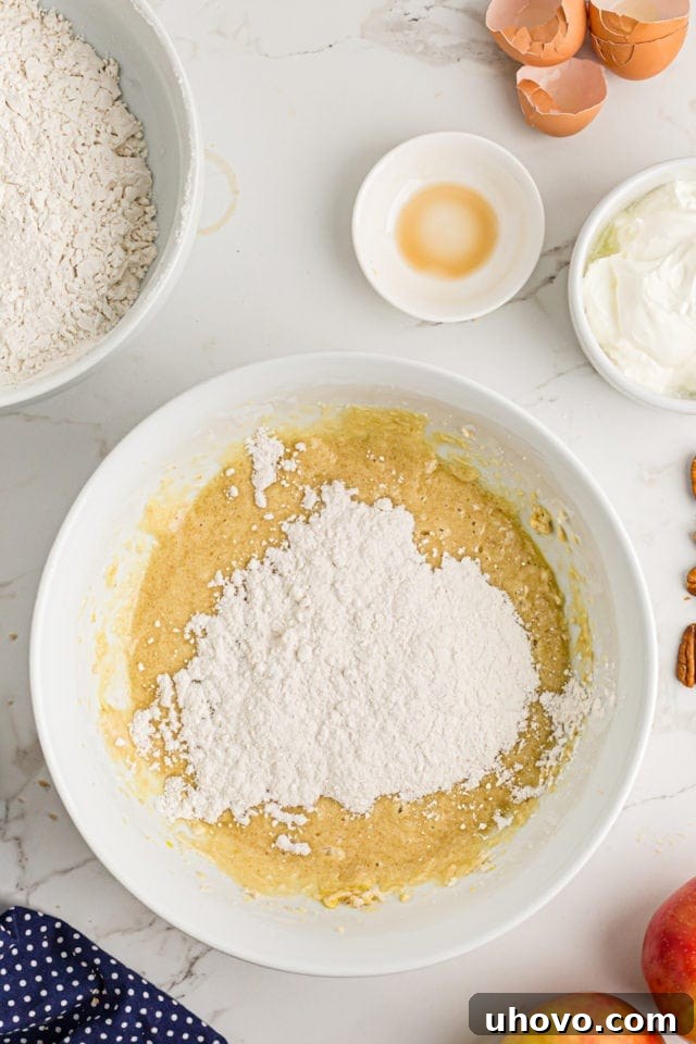 Overhead view of dry ingredients being gradually added to the wet batter mixture in a mixing bowl