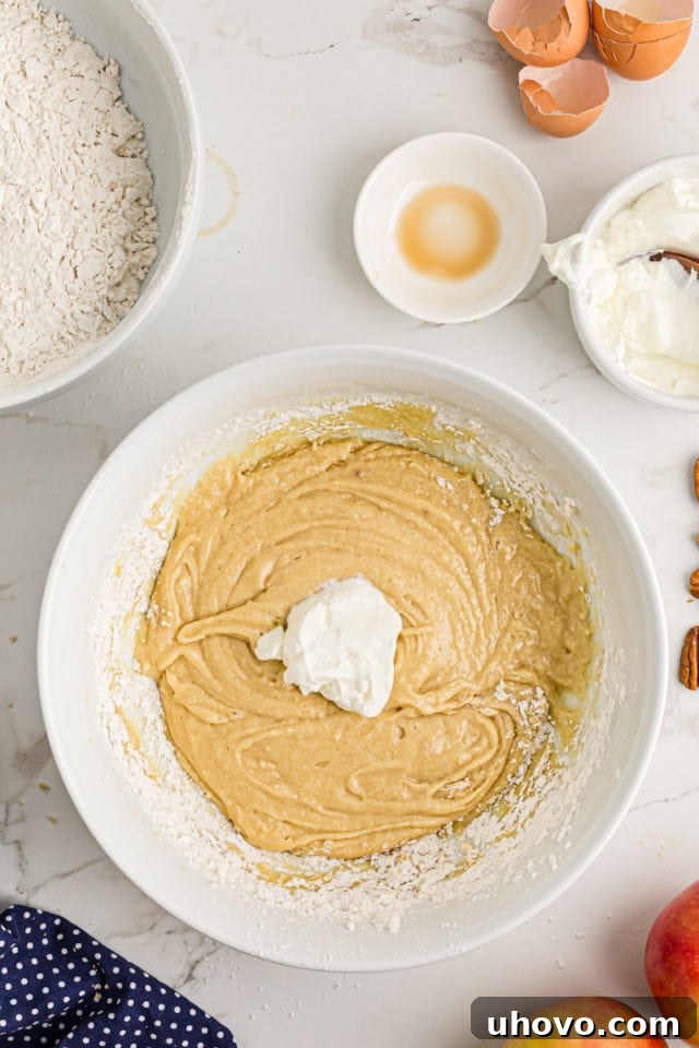 Overhead view of sour cream being folded into the coffee cake batter in a mixing bowl