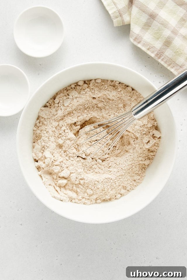 Overhead view of a white bowl containing whisked dry ingredients for banana nut muffins, showing a consistent, light-colored mixture.