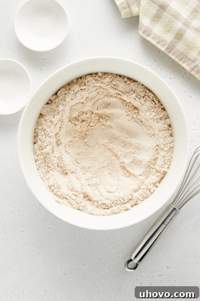Overhead view of the dry ingredients in a white bowl, with a distinct well pressed into the center, ready for the wet ingredients.