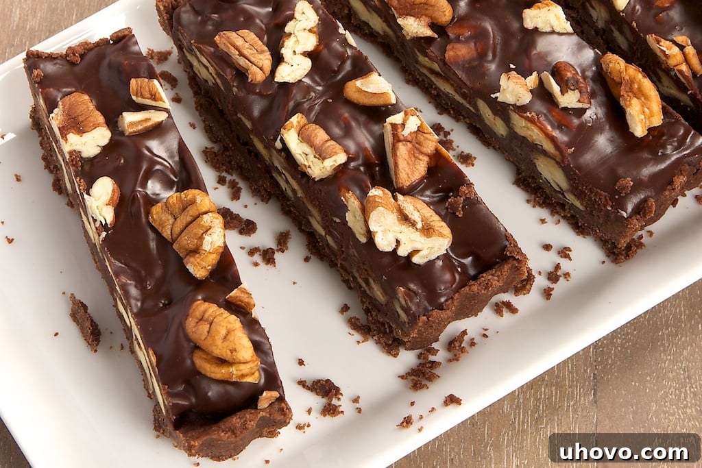 A stunning Chocolate Pecan Tart, perfectly sliced and displayed on a white tray, highlighting its golden crust and dark, rich filling with whole pecans on top.