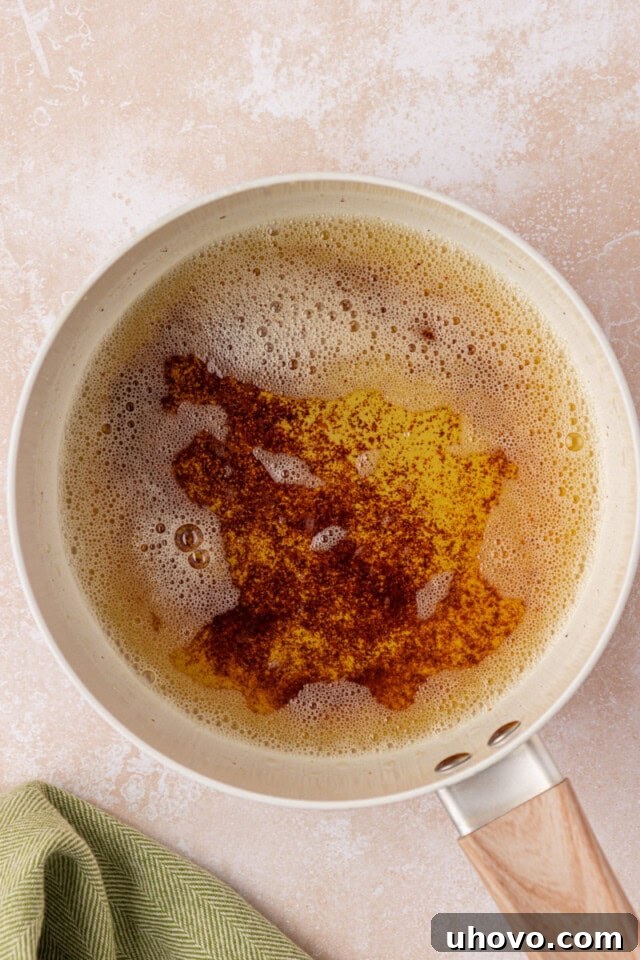 A saucepan on a stovetop, capturing the mesmerizing process of butter transforming into a rich, golden browned butter, with toasted milk solids at the bottom.