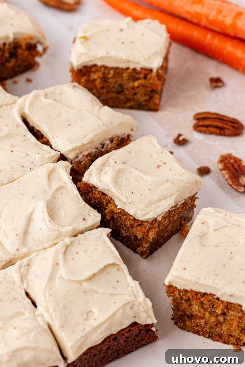 A partially sliced carrot sheet cake, generously covered in a thick layer of browned butter cream cheese frosting, tempting and ready to serve.