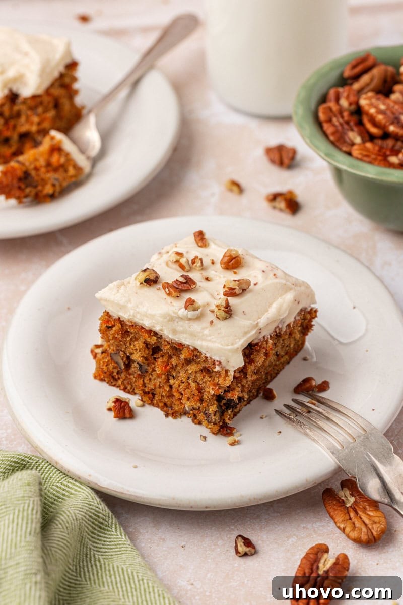 A generous slice of carrot sheet cake with luscious browned butter cream cheese frosting and a sprinkle of chopped nuts, a perfect dessert.