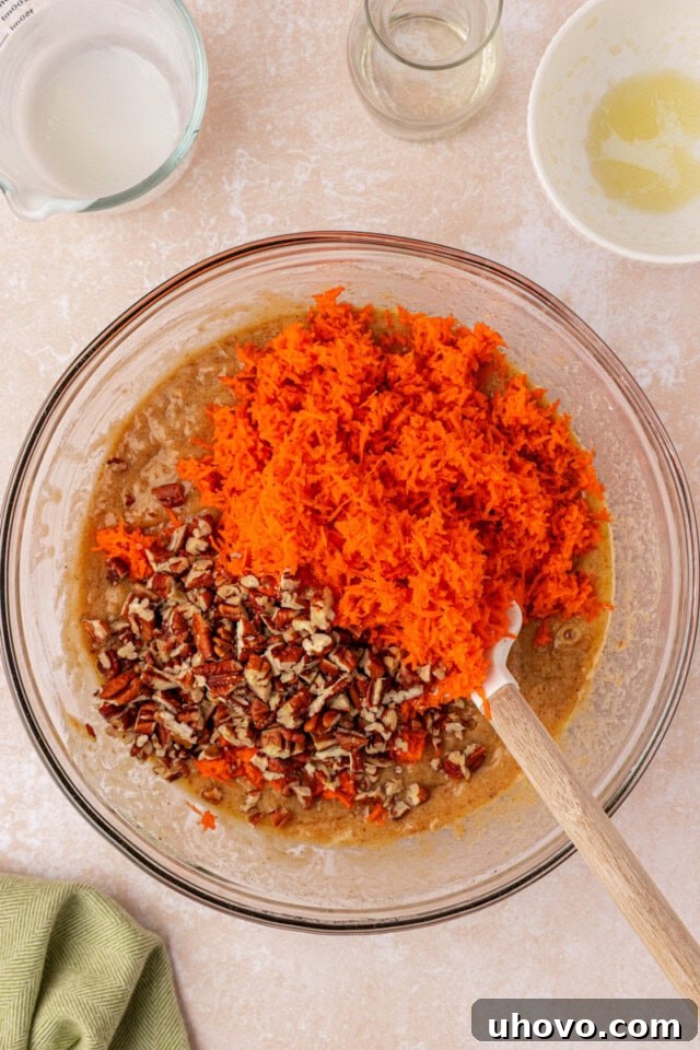 A visual guide to gently folding grated carrots and optional chopped nuts into the carrot cake batter, ensuring even distribution.