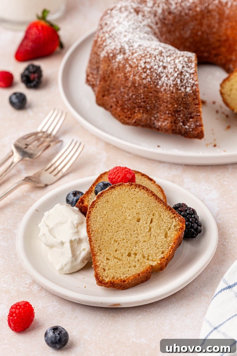Two generous slices of buttermilk pound cake served on a white plate, garnished with fluffy whipped cream and a vibrant mix of fresh berries.