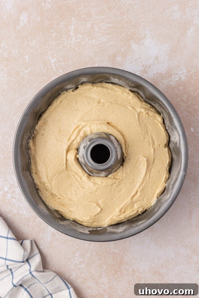 Overhead view of buttermilk pound cake batter evenly spread into a greased Bundt pan, ready for baking.
