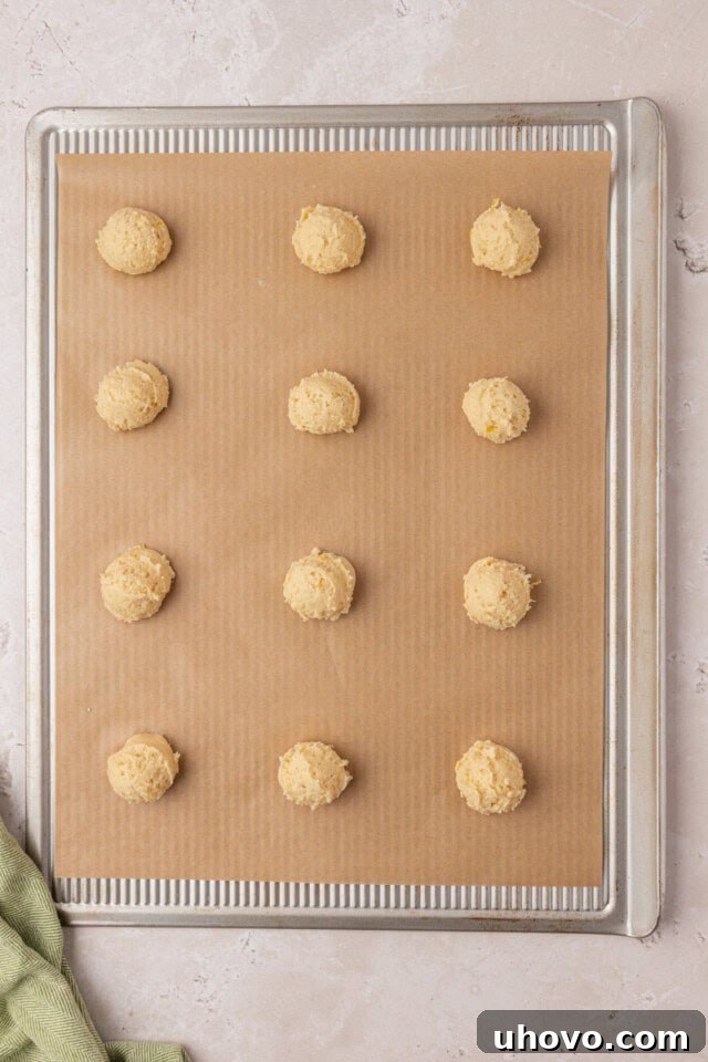 overhead view of ricotta cookies scooped onto a parchment-lined baking sheet