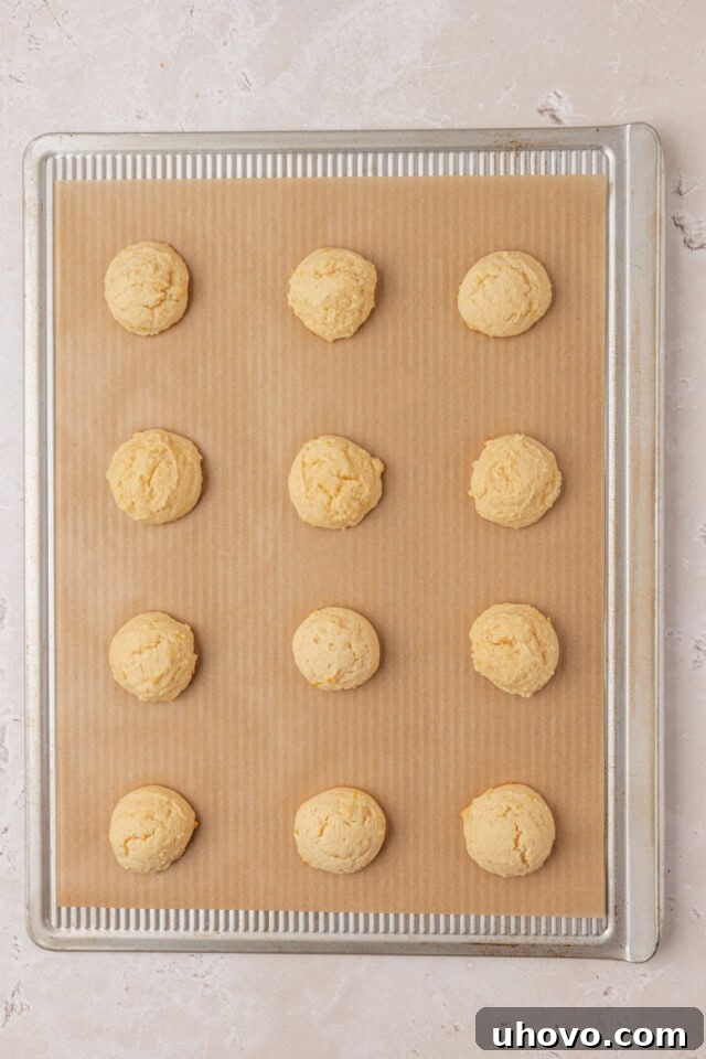 overhead view of freshly baked Italian ricotta cookies on a lined baking sheet