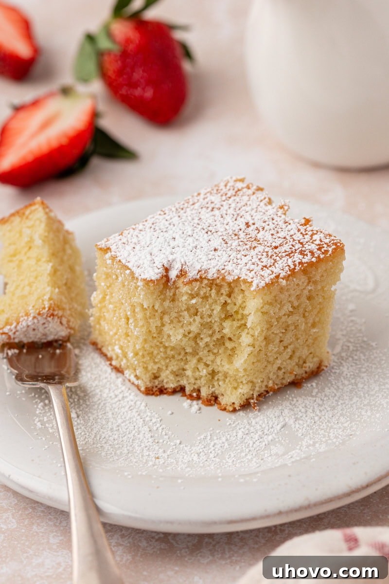 A tantalizing close-up of a slice of hot milk cake, featuring a fork with a perfect bite, highlighting its soft, airy texture and inviting taste.