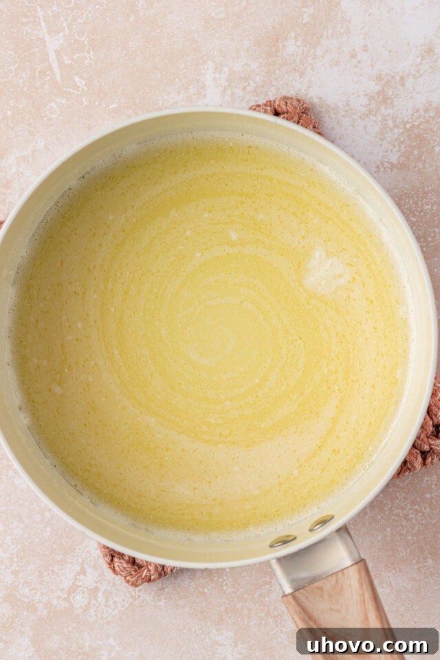 An overhead shot capturing milk and butter heating in a small saucepan, with gentle steam rising, indicating the perfect temperature for the next step in the cake recipe.