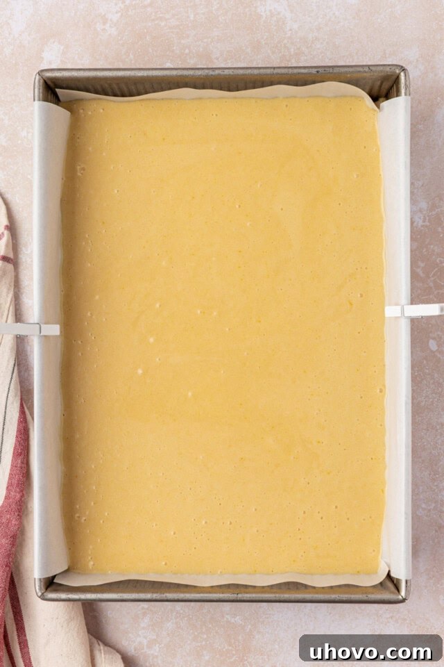 An overhead view of the hot milk cake batter, perfectly smooth and pourable, settled evenly in a greased 9x13 inch baking pan, ready for the oven.