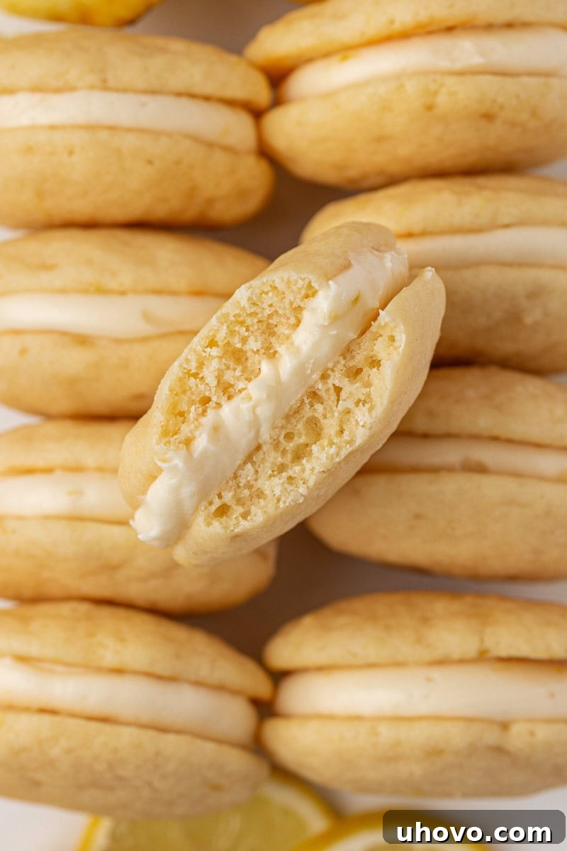 Close-up of a single lemon whoopie pie revealing the generous layer of creamy lemon filling between two soft cake cookies.