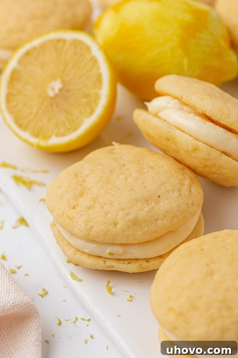 A trio of perfectly assembled lemon whoopie pies with creamy filling, neatly arranged on a pristine white surface, highlighting their inviting appearance.