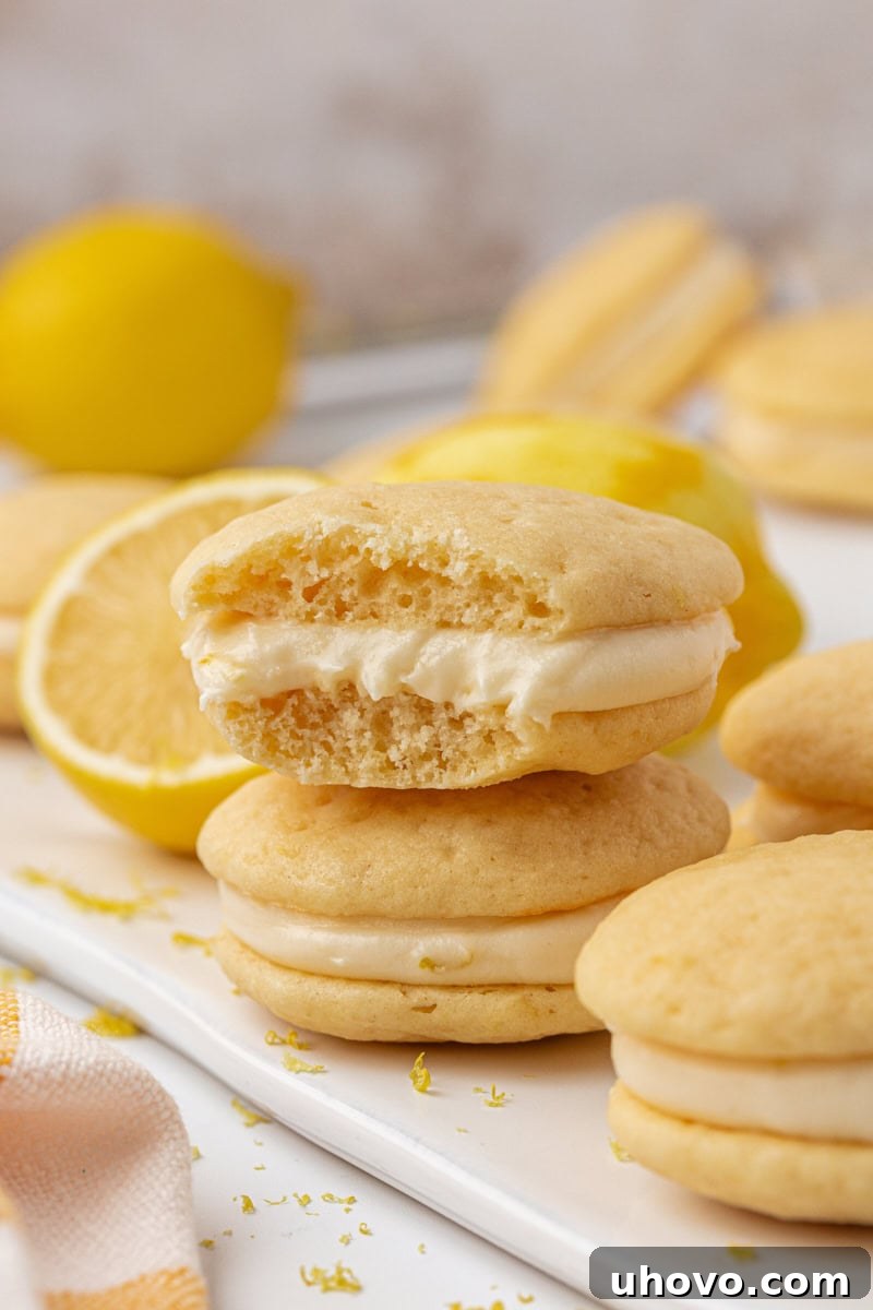 A lemon whoopie pie with a bite missing, clearly showing the thick, creamy lemon filling and the soft, cake-like texture of the cookies.