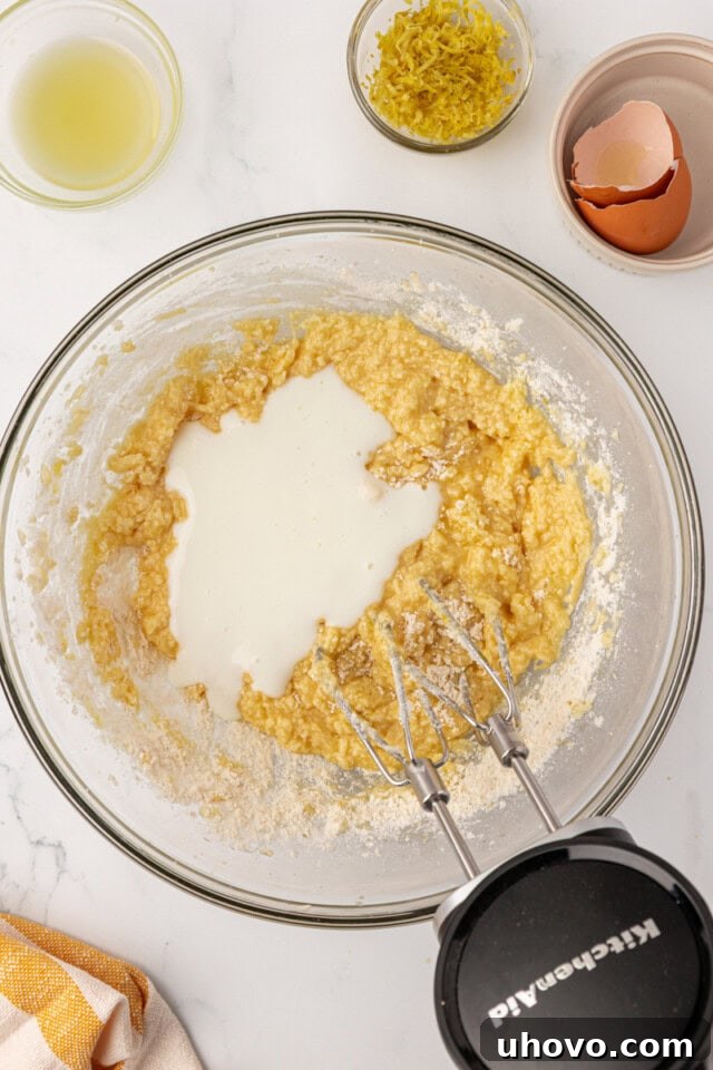 Buttermilk being poured into the lemon whoopie pie dough, alternating with dry ingredients, to create a smooth batter.