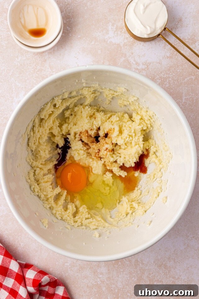 overhead view of egg, vanilla, and almond extract added to creamed butter and sugar